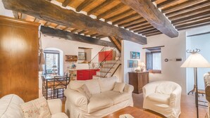 A cozy living room with a wooden ceiling, a dining area with a red cabinet, and a staircase leading upstairs. - Cozy home in Todi PG with WiFi (Todi PG)