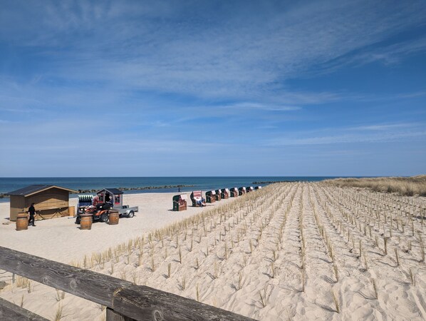 A beach with sand dunes, a wooden fence, and beach huts. - Vacation apartment Sonnensuite (Wustrow)