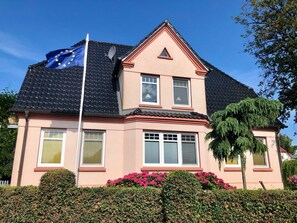A two-story house with a sloped roof, a satellite dish, and a flagpole with a flag. - Vacation apartment Sonnensuite (Wustrow)
