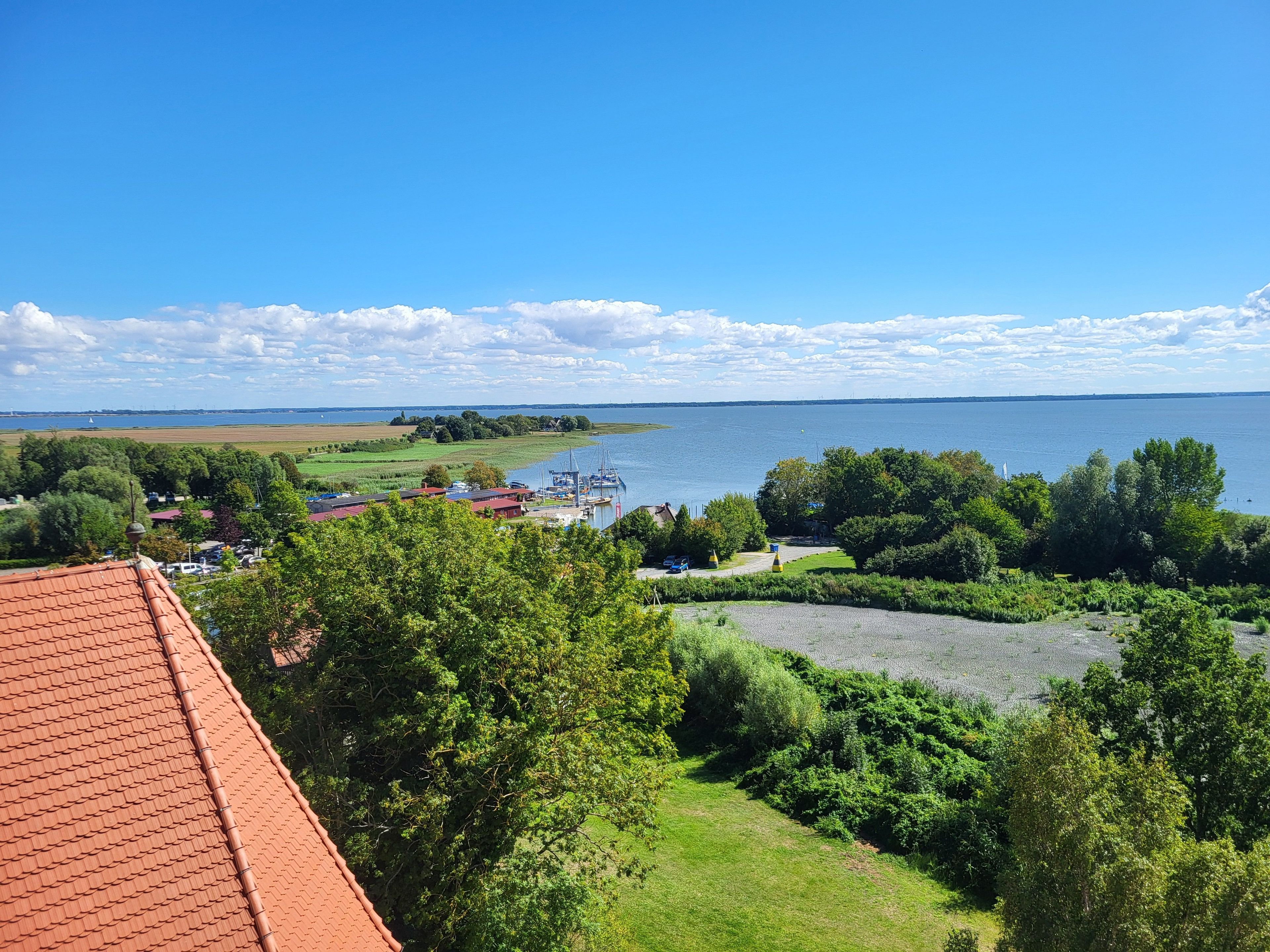 A coastal view with a marina, green fields, and a clear sky.