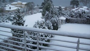 A residential area with snow-covered houses and trees, a small white gazebo, and a view of the sea. - VO 3; 2-space; EC; Terrace; 42m² - Gästehaus Vogelsang (Sierksdorf)