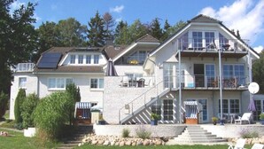 A two-story house with a balcony, a staircase, and a lawn. - VO 3; 2-space; EC; Terrace; 42m² - Gästehaus Vogelsang (Sierksdorf)