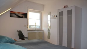 A bedroom with a bed, a chair, a window, a radiator, a wardrobe, and a mirror. - Vacation apartment Schäfer (Vöhl)