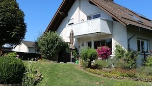A house with a sloped roof, a visible satellite dish, and a well-maintained garden. - Vacation apartment Schäfer (Vöhl)