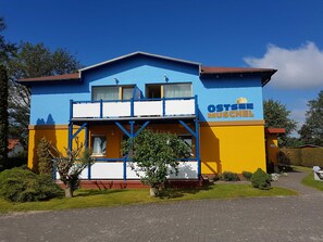 A two-story building with a blue and yellow facade, a sign reading 'OSTSEEL MUSCHEN,' and a visible balcony. - Apartment 6 - Baltic Sea shell (Zinnowitz)