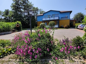 A building with a blue and yellow facade, a covered outdoor area, and a parking lot. - Apartment 6 - Baltic Sea shell (Zinnowitz)