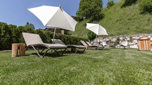 A grassy outdoor area with lounge chairs and white umbrellas.