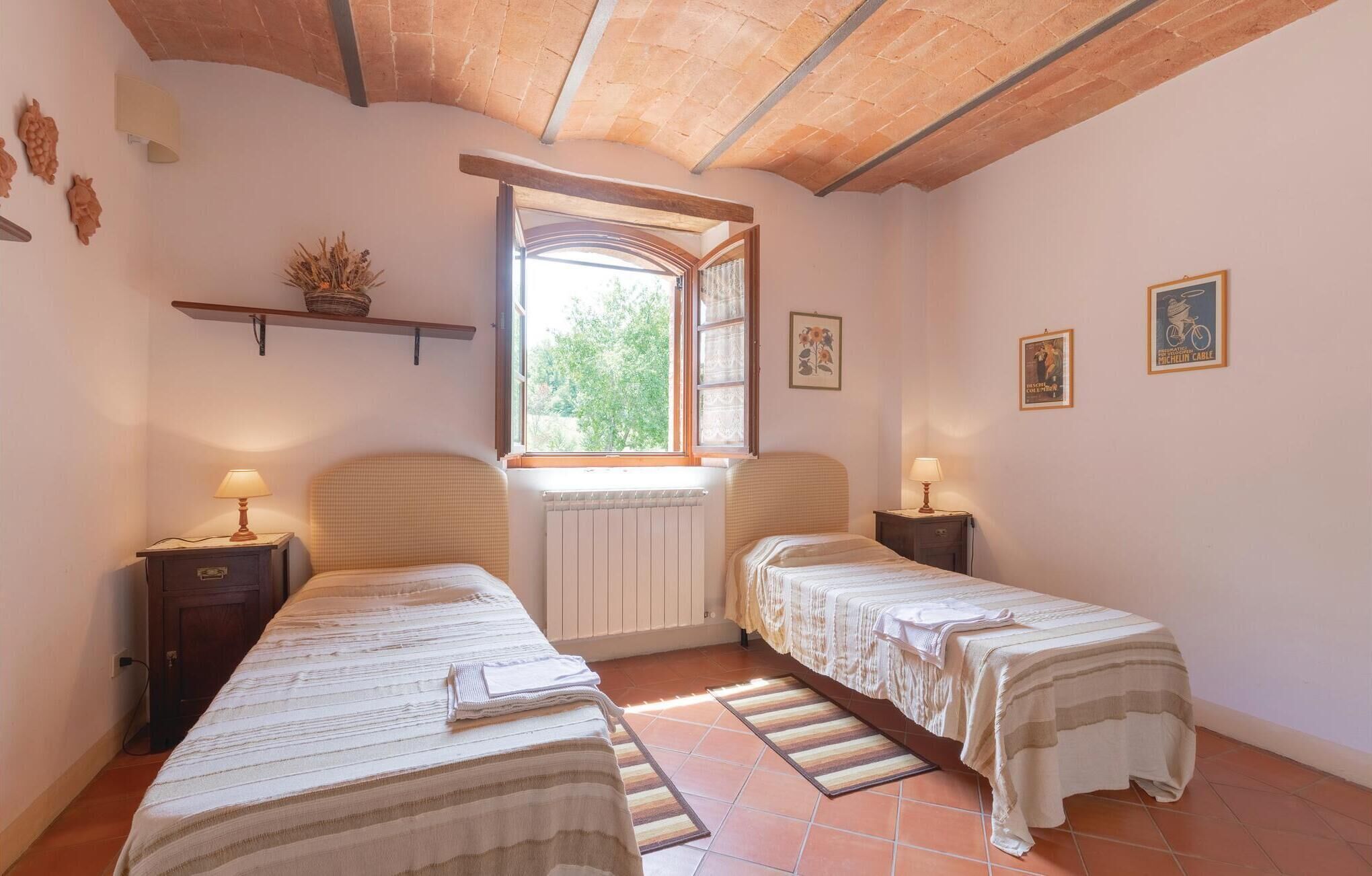 A bedroom with two beds, a window, and a radiator.