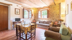 A cozy room with a wooden ceiling, stone walls, a dining table with chairs, a sofa, and a television. - Amazing apartment in S.Vito In Monte TR (S.Vito In Monte TR)