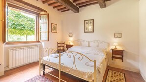 A bedroom with a bed, bedside tables, a radiator, and a window with a view of greenery. - Amazing apartment in S.Vito In Monte TR (S.Vito In Monte TR)