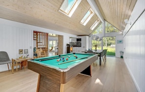 A spacious indoor area with a pool table, a dining table with chairs, and a kitchen area. - 4 bedroom lovely home in Blåvand (Blåvand)