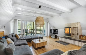 A spacious living room with a high ceiling, a large sofa set, a wooden coffee table, a TV, and a fireplace. - 4 bedroom lovely home in Blåvand (Blåvand)