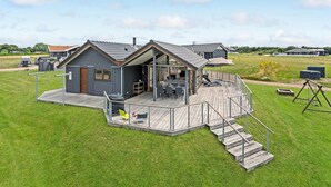 Ett modernt hus med en terrass, en inglasad uteplats och ett litet utomhuskök.