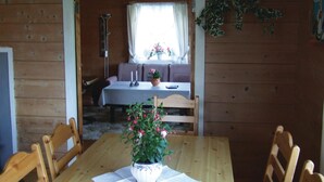 A wooden dining table with chairs, a potted plant, and a tablecloth.