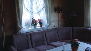 A cozy room with a sofa, a table with candles, and a window with flowers.