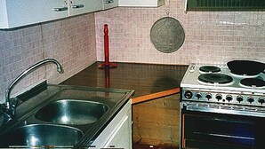 A kitchen with a sink, stove, and cabinets.