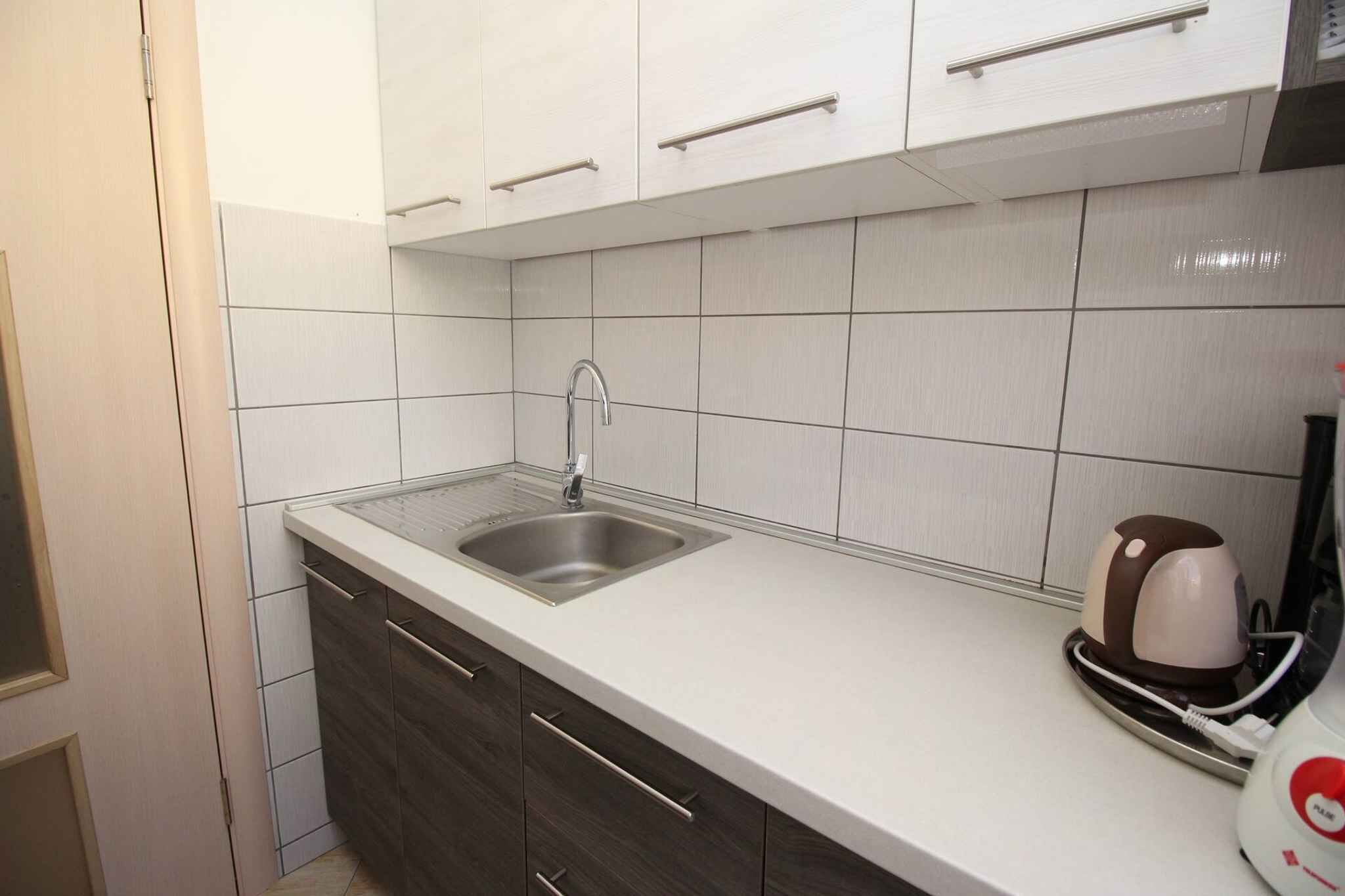 Eine Küche mit weißen Schränken, einer Edelstahl-Spüle und einer Kaffeemaschine auf der Arbeitsfläche.