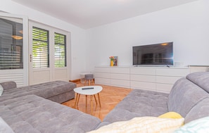 A modern living room with grey sofas, a flat-screen TV, and a small round table. - Stunning home in Tribunj-Sovlje (Tribunj-Sovlje)