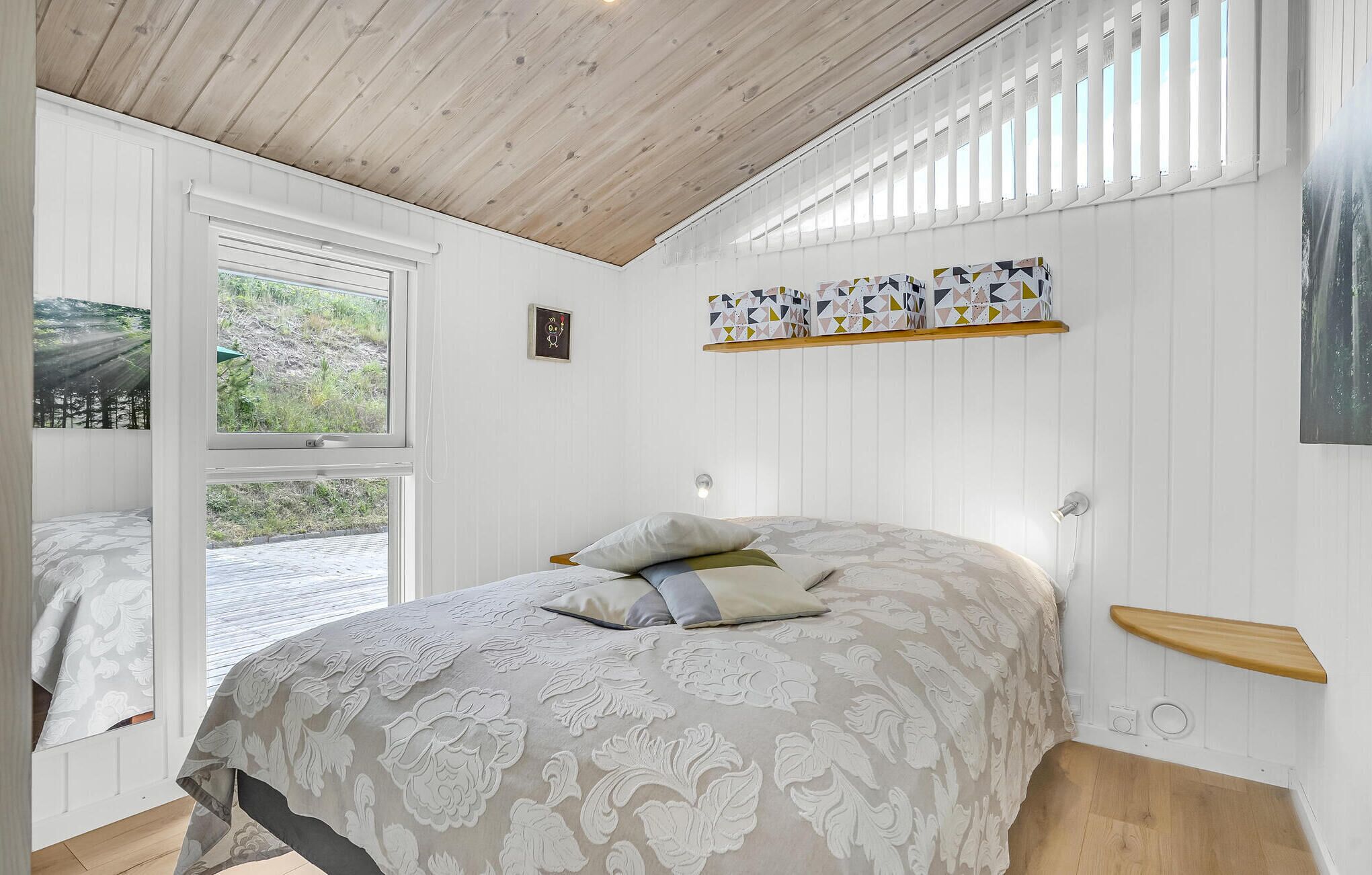 Een slaapkamer met een bed, een raam en een plank met dozen met een patroon.