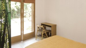 A room with a bed, a desk, and a chair. There is a sliding glass door leading to an outdoor area with greenery. - Lovely home in Cazevieille with kitchen (Cazevieille)