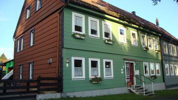 A two-story building with a green facade, white window frames, and a red door.
