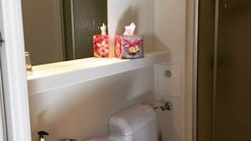 Ein Badezimmer mit einem weißen Waschbecken, einer Toilette, einem Spiegel und einem Regal mit zwei Taschentuchboxen.