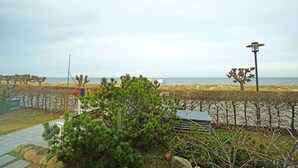 Eine Küstenansicht mit einem Pfad, der zum Strand führt, einer kleinen Struktur und einem Laternenpfosten.