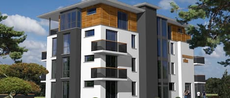 A modern multi-story building with balconies, large windows, and a sign reading 'Strandhaus Düne'.