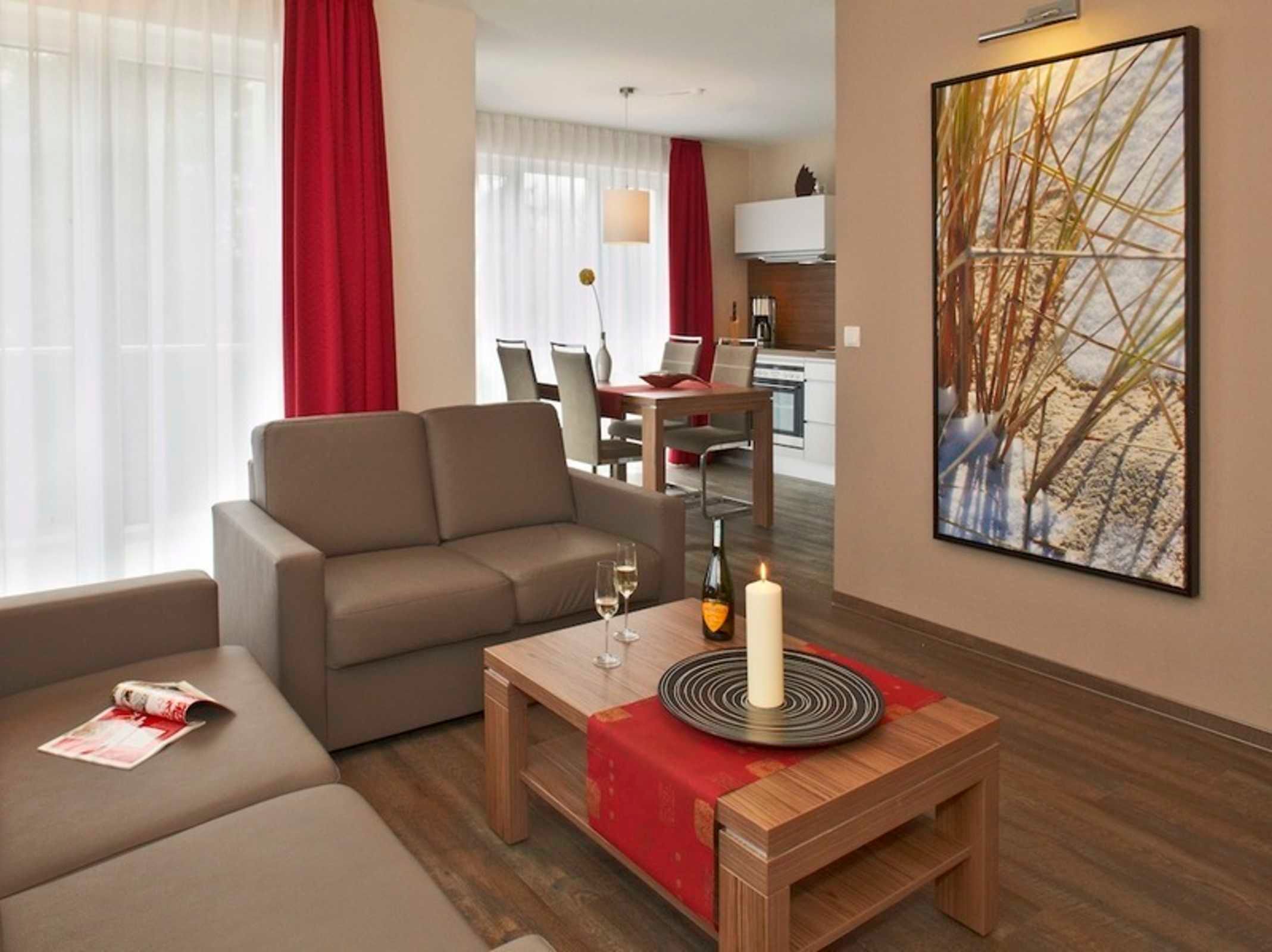 Ein modernes Hotelzimmer mit einer Couch, einem kleinen Holztisch mit Kerze und einem Bild an der Wand.