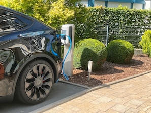 Un véhicule électrique noir en cours de recharge à une borne.