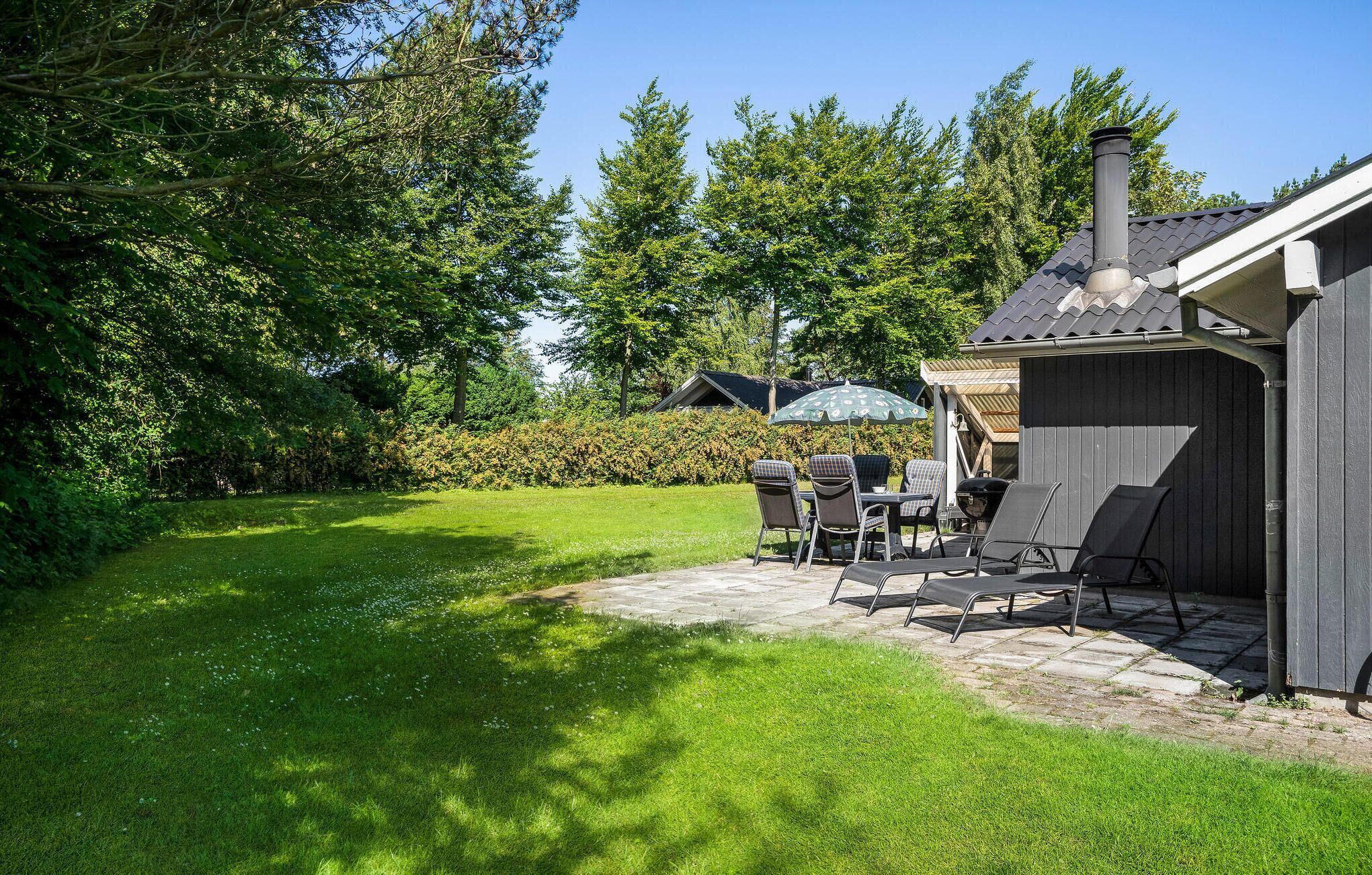 Un jardin avec une terrasse, du mobilier d’extérieur et un barbecue.