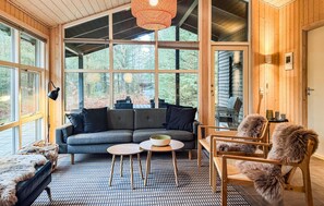 A cozy room with a grey sofa, a round table, and a wooden chair with fur throw.