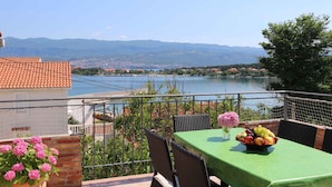 A balcony with a table set for dining, overlooking a lake and mountains. - Holiday apartment with barbecue, internet and air conditioning (Šilo)