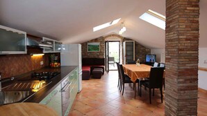 A kitchen with a gas stove, a sink, and a dining area with a table and chairs. - Holiday apartment with barbecue, internet and air conditioning (Šilo)