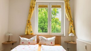 A bedroom with a bed, two bedside lamps, a window with curtains, and a radiator. - *Windrose 23 measure GM 69552 - Windrose 23 - SNR: 10 (Graal-Müritz)