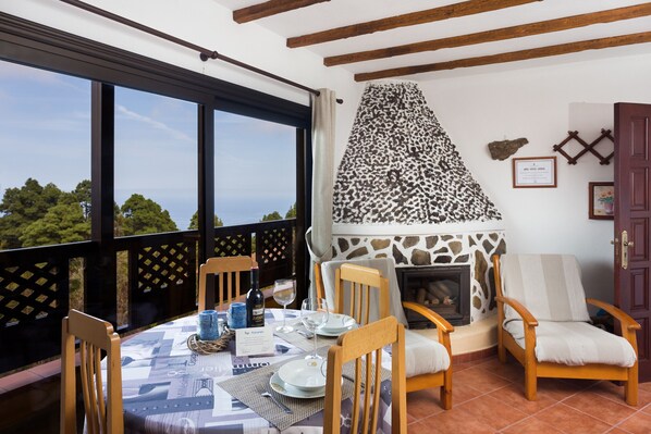 Un comedor con una mesa dispuesta para cuatro personas, una chimenea y vistas al exterior.