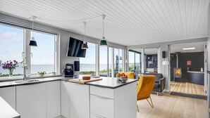 A modern kitchen with a large island, a coffee machine, and a view of the sea.