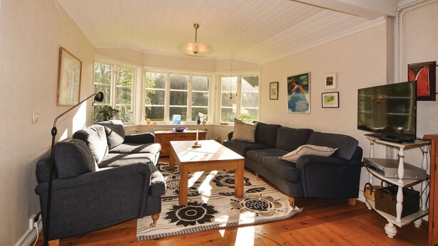 A living room with two sofas, a coffee table, a TV on a stand, and a large window with multiple panes. - 4 bedroom stunning home in Färgelanda (Färgelanda)