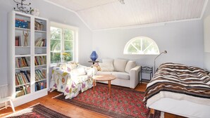 A cozy room with a bookshelf, a sofa, a patterned rug, and a large window. - 4 bedroom stunning home in Färgelanda (Färgelanda)