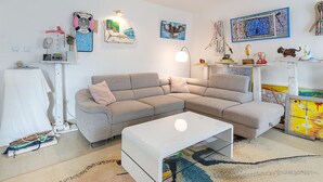 A modern living room with a grey sectional sofa, a white coffee table, and a patterned rug.