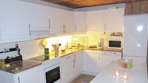 A kitchen with white cabinets, a stove, an oven, a microwave, and a coffee maker. - Lovely home in Hede with sauna (Hede)