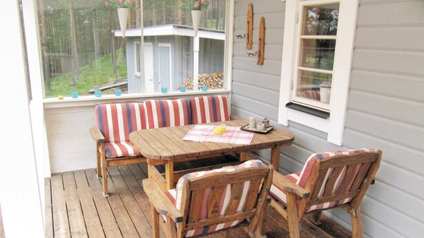 A covered porch with a wooden table and striped cushioned benches. - Lovely home in Hede with sauna (Hede)