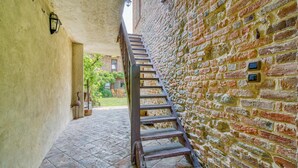 A narrow stone staircase leading to an upper level, flanked by a brick wall and a plain wall with a light fixture. - Lovely home in Aramengo AT (Aramengo AT)