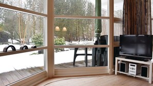 A room with large windows, a wooden floor, a television, and a small table with chairs. - Gorgeous home in Væggerløse with WiFi (Væggerløse)