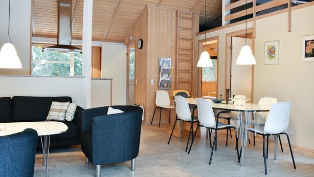 A modern interior with a black sofa, a dining table with chairs, and pendant lights. - Gorgeous home in Væggerløse with WiFi (Væggerløse)