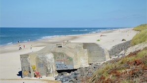 Ein Strand mit einer Betonkonstruktion, die mit Graffiti bemalt ist und ein Schild trägt.