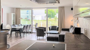 Ein modernes Wohnzimmer mit Essbereich, einer Küche und einem Balkon mit Blick auf die Nachbarschaft.