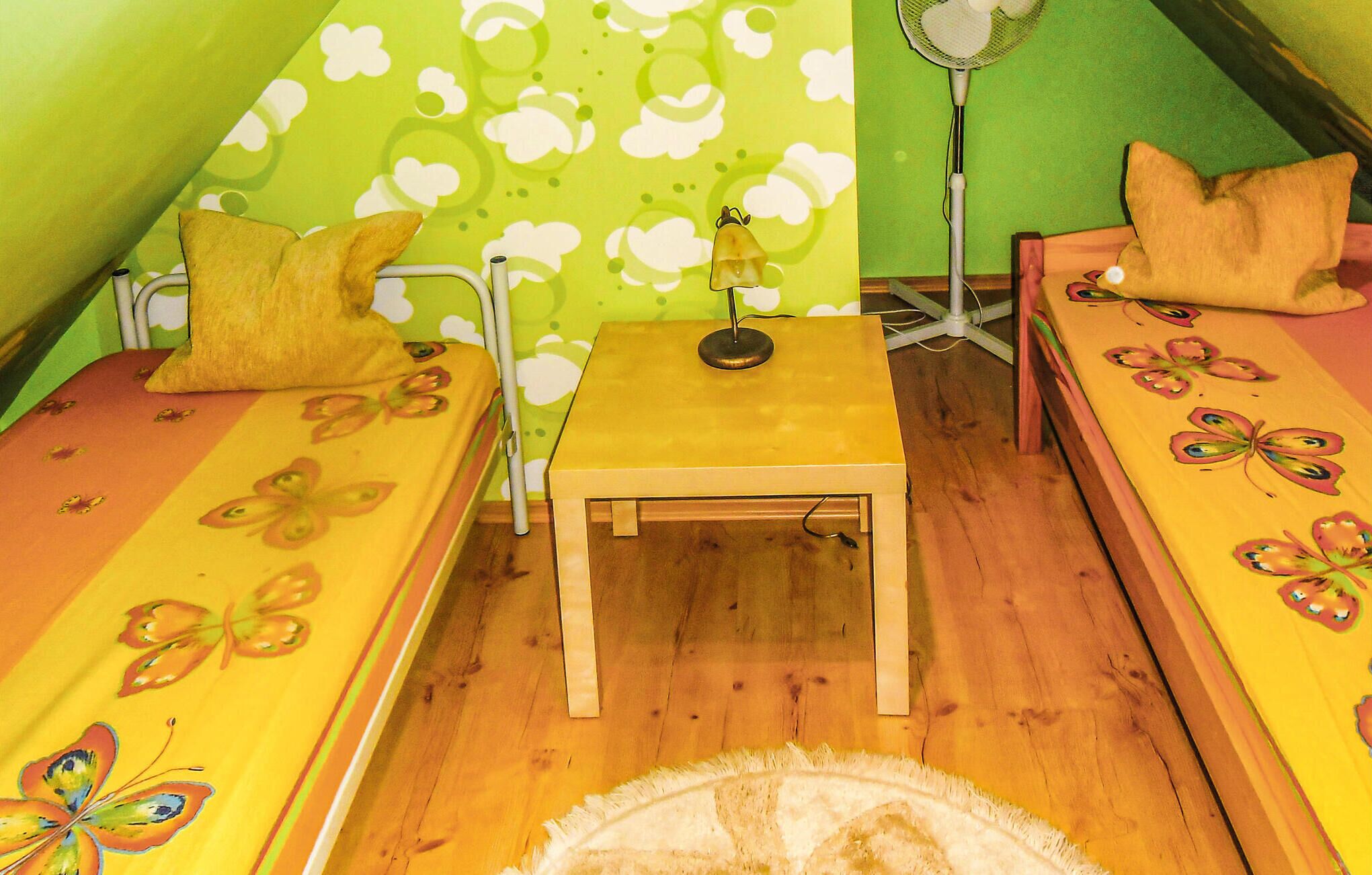 A small, cozy room with two single beds, a small table, and a fan.