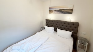 Een slaapkamer met een groot bed, een hoofdeinde, twee nachtkastjes en een wanddecoratie.