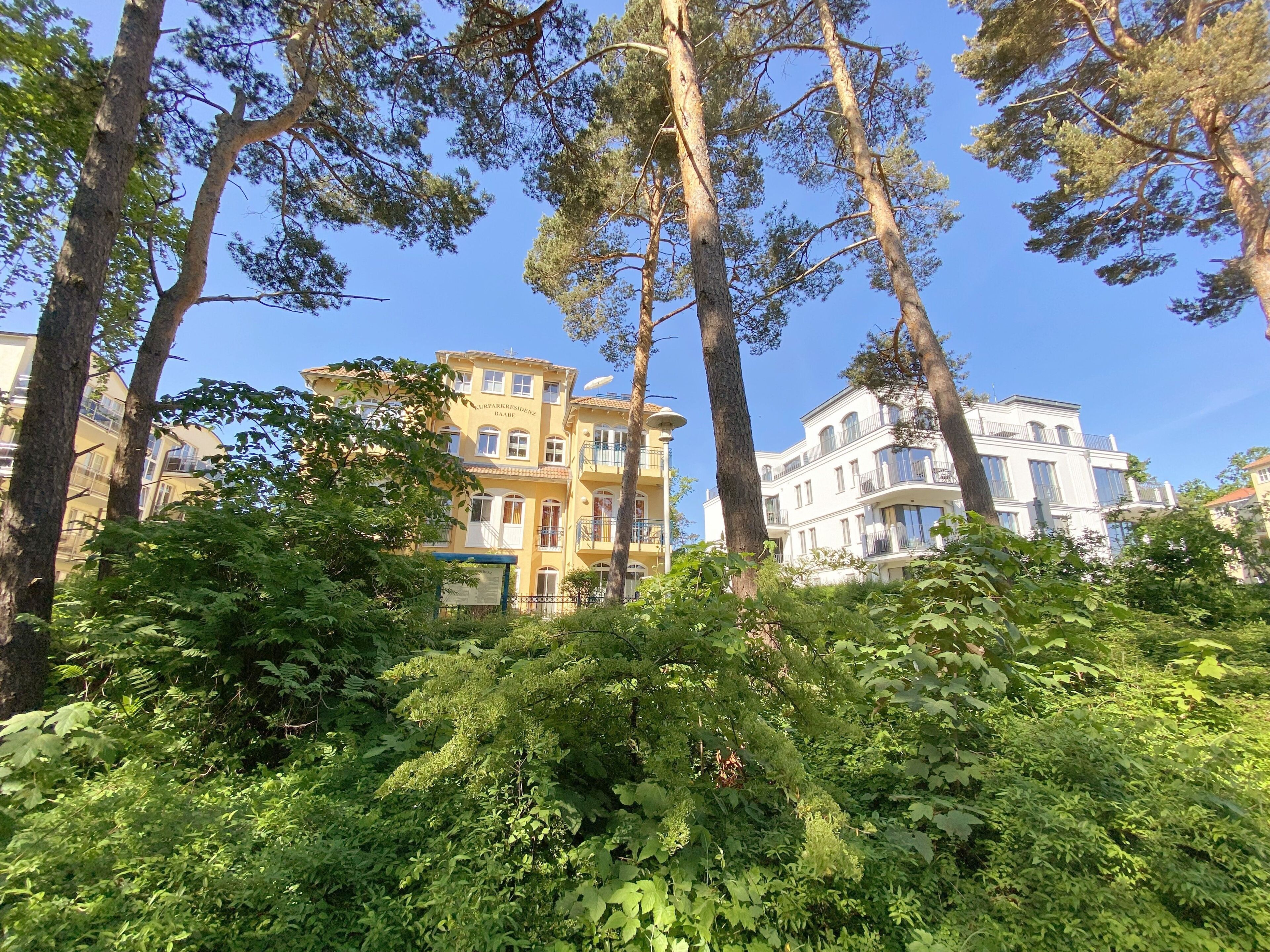 Ein mehrstöckiges Gebäude mit Balkonen und einem üppigen, grünen Garten im Vordergrund.